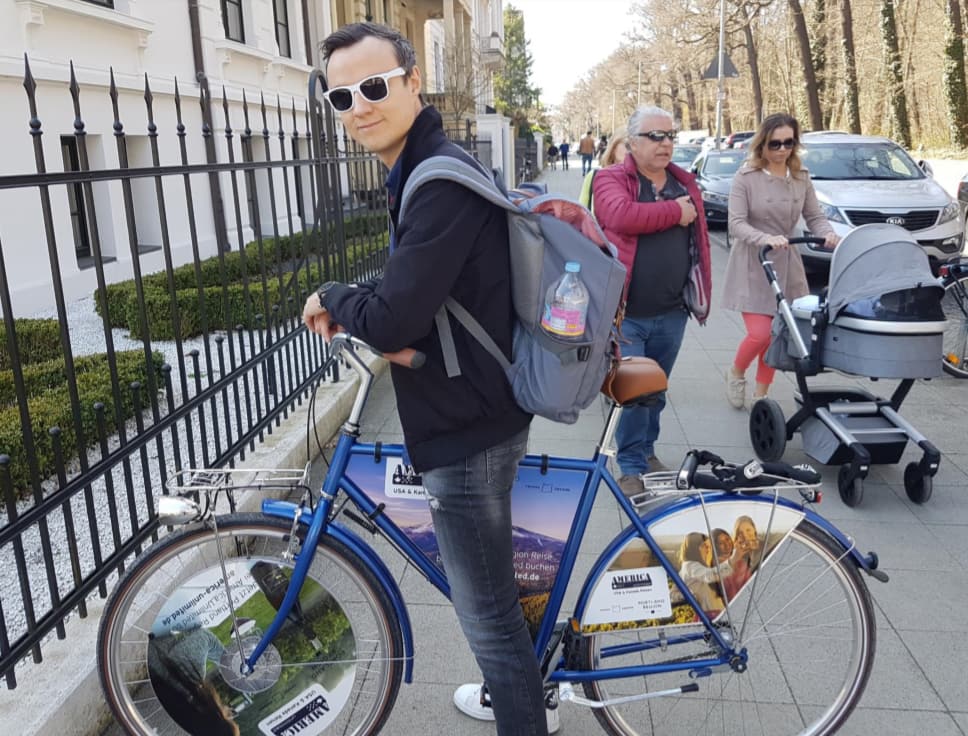 A man in white sunglasses, posing for a picture with a Portland Region-branded bicycle.