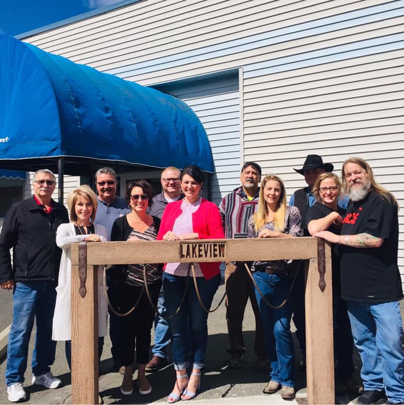 A group of 11 people, standing around a wooden sign which displays the word 'Lakeview'