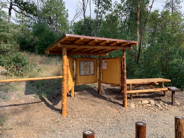 A wooden kiosk containing informational and directional trail signage.