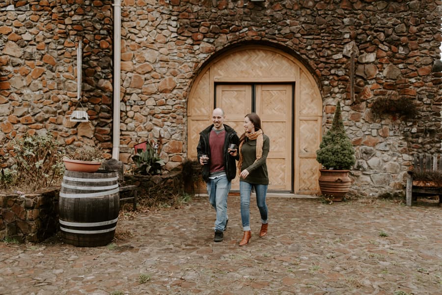 A couple expresses joy as they walk out of the doors of a wine cellar.