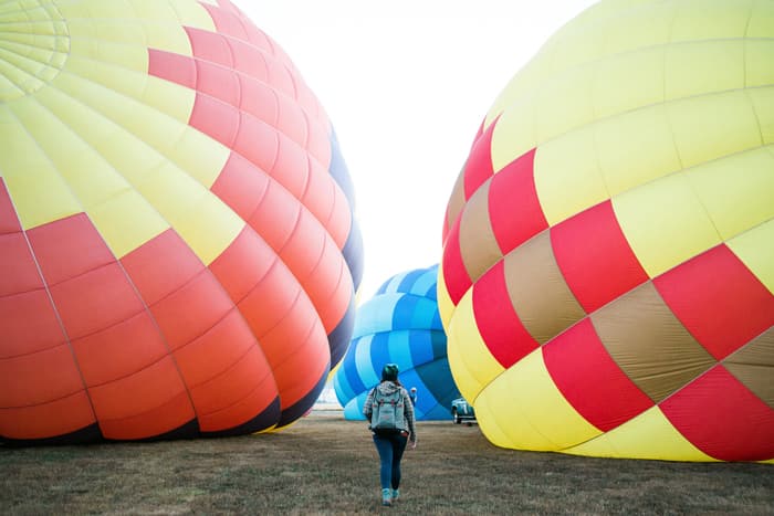 A man walks in the crevice between three grounded hot air balloons.